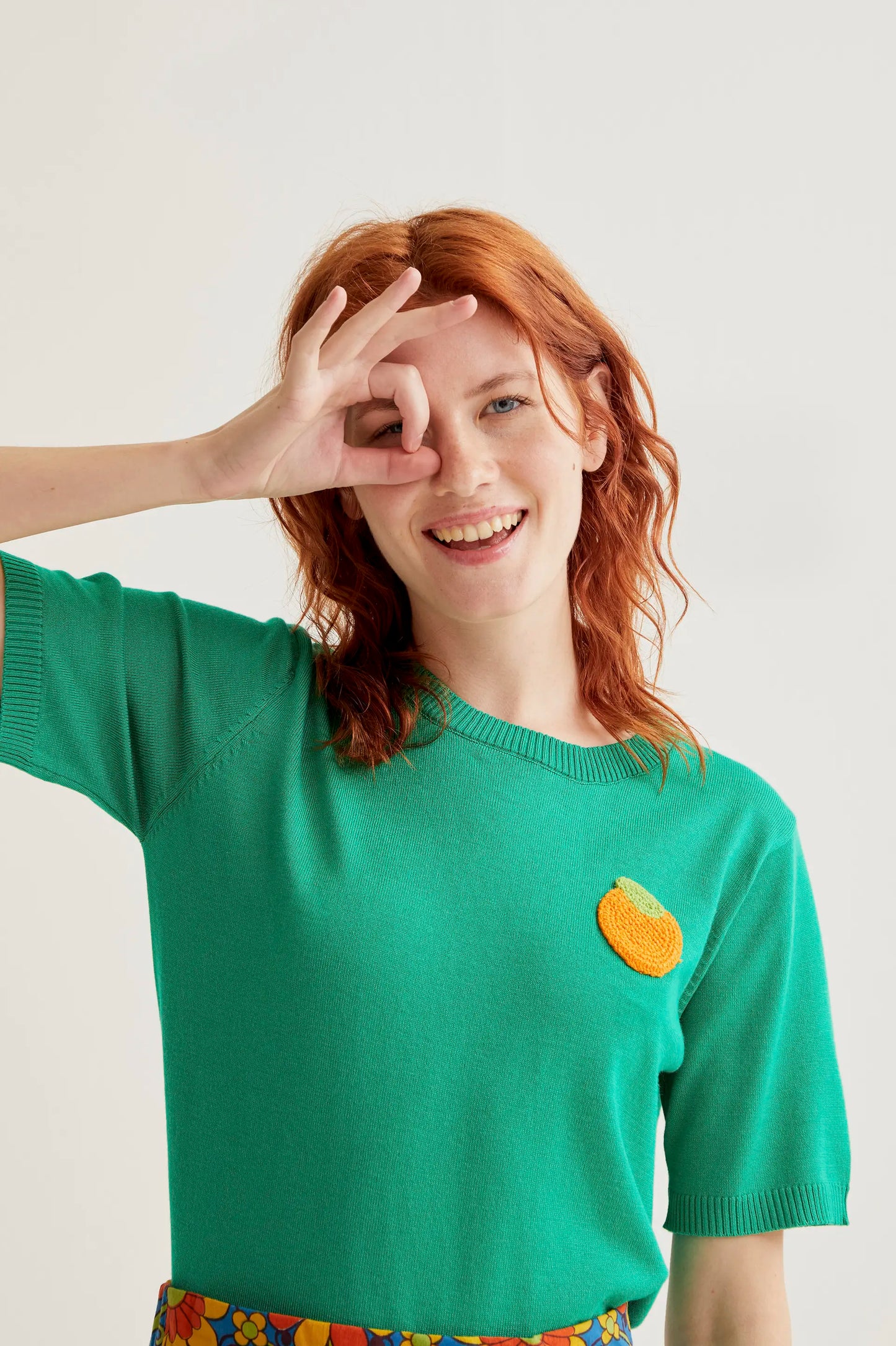 Top in maglia verde con ricamo arancione